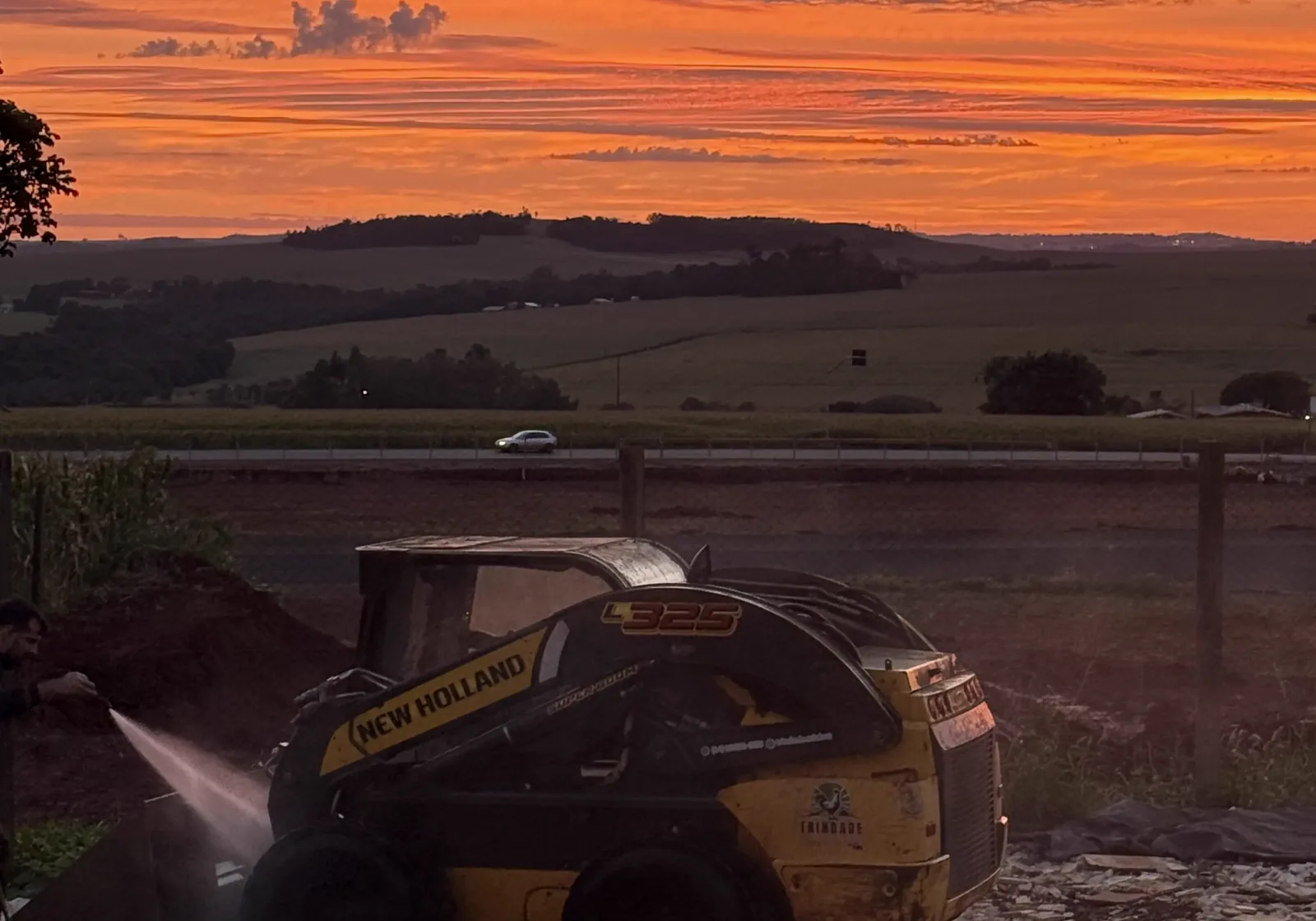 Máquina da Trindade Agro trabalhando no campo ao pôr do sol
